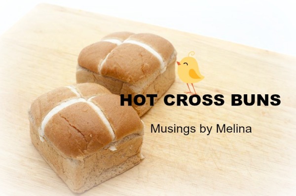 Two fresh glazed Hot Cross Buns on a wooden cutting board with copyspace